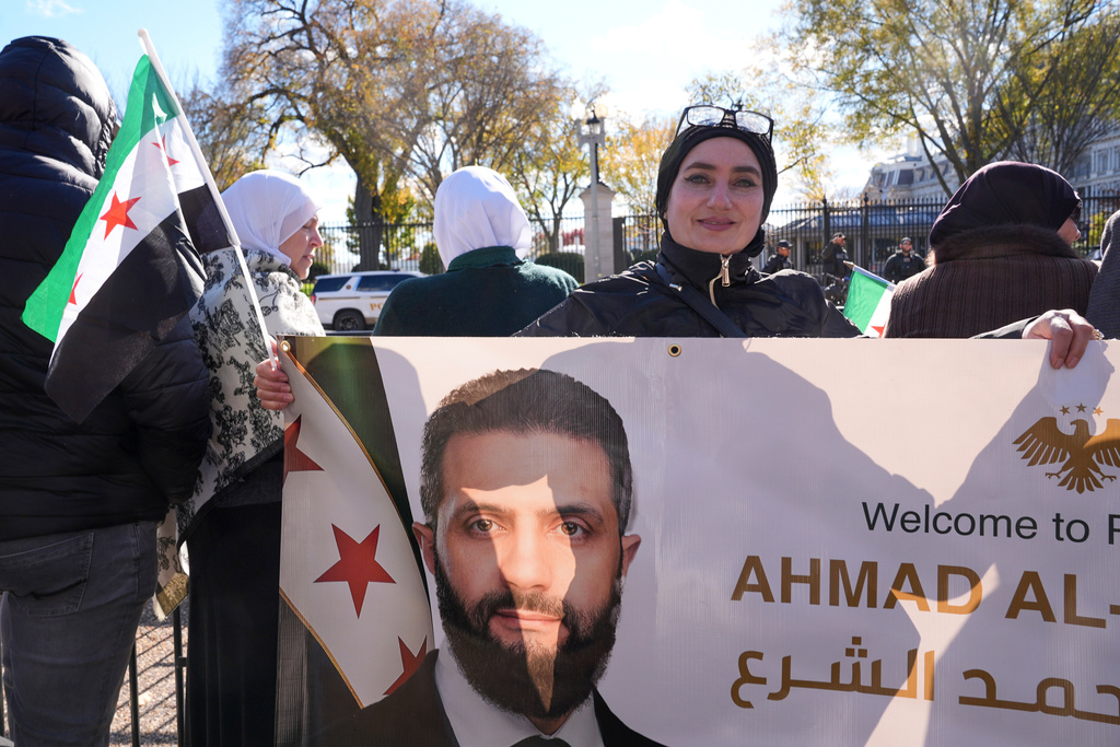 Motiah Boustany, of Charlestown, W.Va., holds a banner depicting Syria's President Ahmed al-Sharaa outside of the White House, as al-Sharaa meets with President Donald Trump, Monday, Nov. 10, 2025, in Washington. (AP Photo/Jacquelyn Martin)