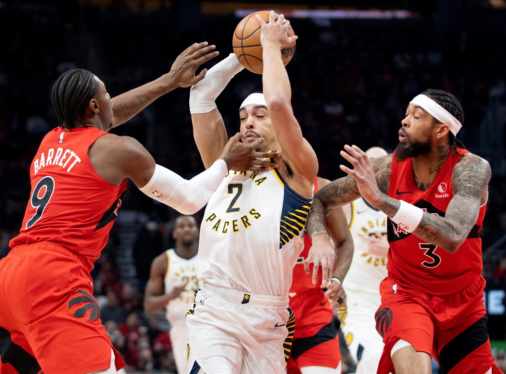 Indiana Pacers guard Andrew Nembhard (2) is double-teamed by Toronto Raptors' Brandon Ingram (3) and R.J. Barrett (9) as he drives to the hoop during first-half NBA basketball game action in Toronto, Sunday Feb. 8, 2026. (Frank Gunn/The Canadian Press via AP)