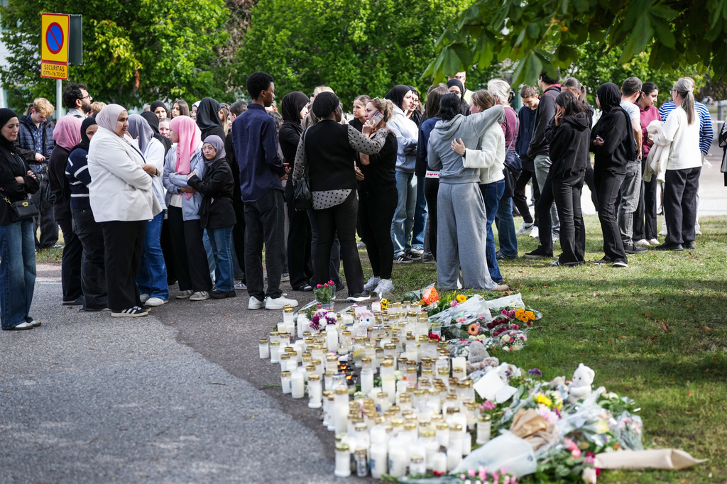 People leave flowers and candles at a makeshift memorial outside a school in Fagersta, Sweden, Saturday Aug. 22, 2026, the day after an 18-year-old with a sword attacked the school killing one person and seriously injuring two others. (Magnus Lejhall/TT via AP)