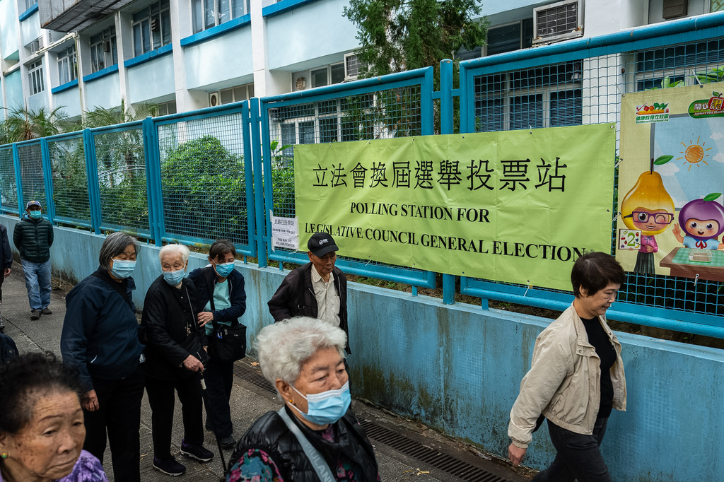 People walk past a polling station near the site of the fire at Wang Fuk Court in the Tai Po district during the Legislative Council General Election in Hong Kong on Sunday, Dec. 7, 2025. (AP Photo/Chan Long Hei)