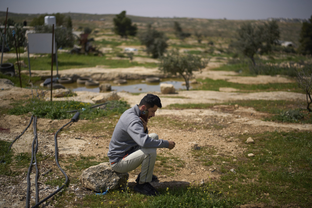 FILE - Basel Adra, one of the directors of the Oscar winner documentary "No Other Land", speaks on the phone as he sits in an area near the house of Palestinian co-director Hamdan Ballal, in Susiya in Masafer Yatta, south Hebron hills, March 25, 2025. (AP Photo/Leo Correa, File)