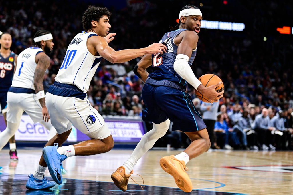 Oklahoma City Thunder guard Shai Gilgeous-Alexander, right, drives against Dallas Mavericks guard Max Christie (00) during the second half of an NBA basketball game, Friday, Dec. 5, 2025, in Oklahoma City. (AP Photo/Gerald Leong)
