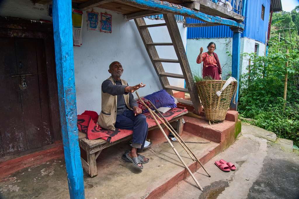 Hari Bahadur Karki, 73, shares his experience about monkeys raiding the village farmland, as Bhawani Khadka, 70, listens while holding a stick she uses to guard her farm against monkeys in Dharamghar, Dolakha district, about 86 kilometers (53 miles) east of Kathmandu, Nepal, Friday, July 24, 2026. (AP Photo/Niranjan Shrestha)