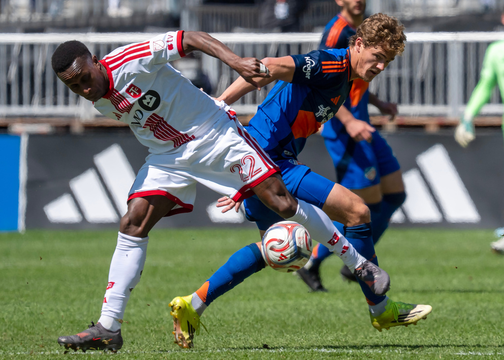 Toronto FC defender Richie Laryea (22) and FC Cincinnati forward Tom Barlow, right, battle for the ball during the first half of an MLS soccer game in Toronto, Saturday, April 11, 2026. (Frank Gunn/The Canadian Press via AP)
