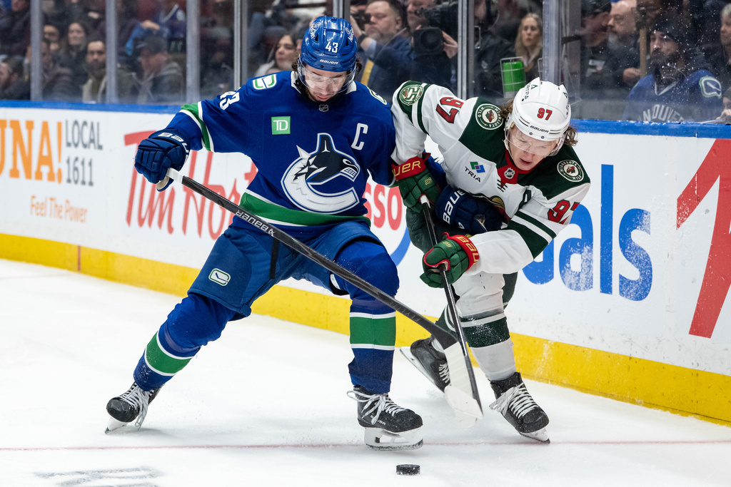 Vancouver Canucks Quinn Hughes (43) and Minnesota Wild Kirill Kaprizov (97) vie for the puck during third period NHL hockey game action in Vancouver, British Columbia, Saturday, Dec. 6, 2025. (Ethan Cairns/The Canadian Press via AP)
