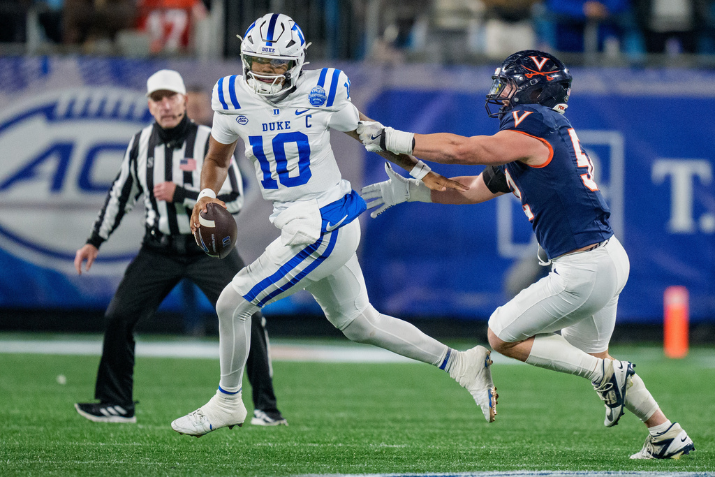 FILE - Virginia defensive lineman Daniel Rickert (52) tries to tackle Duke quarterback Darian Mensah (10) during the Atlantic Coast Conference championship NCAA college football game between Virginia and Duke, Dec. 6, 2025, in Charlotte, N.C. (AP Photo/Jacob Kupferman, File)