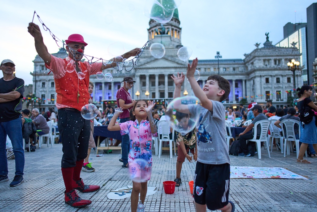 Children play with bubbles during a Christmas dinner organized by labor activists for people in need outside Congress in Buenos Aires, Argentina, Wednesday, Dec. 24, 2025. (AP Photo/Rodrigo Abd)