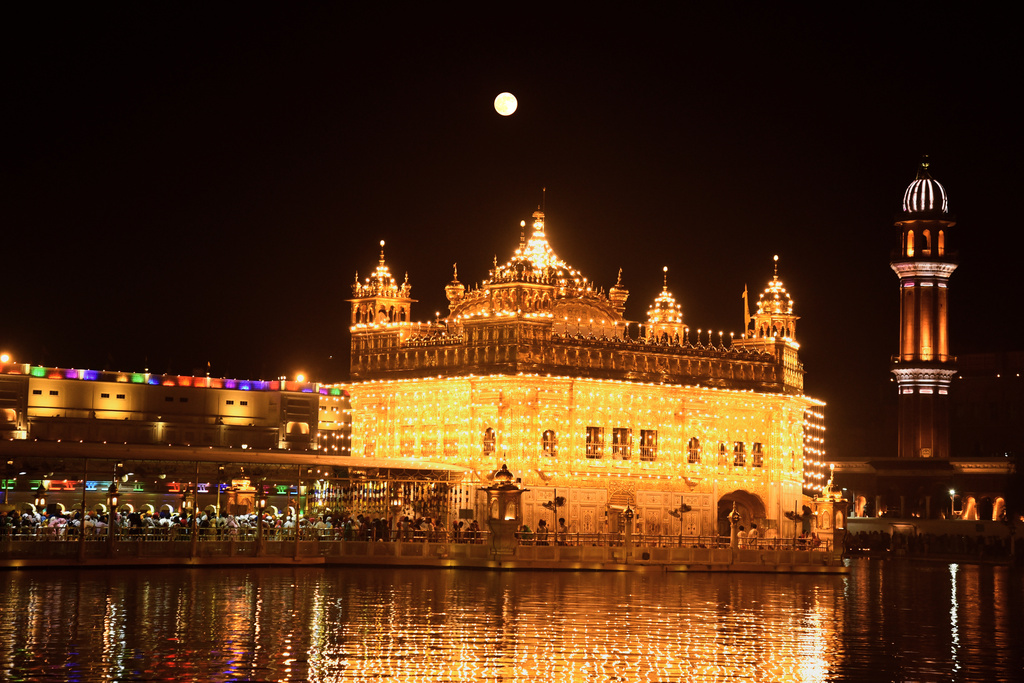 The supermoon rises behind the illuminated Golden Temple as Sikh devotees pray at the to mark the birth anniversary of their first guru, Guru Nanak, in Amritsar, India, Wednesday, Nov. 5, 2025. (AP Photo/Prabhjot Gill)