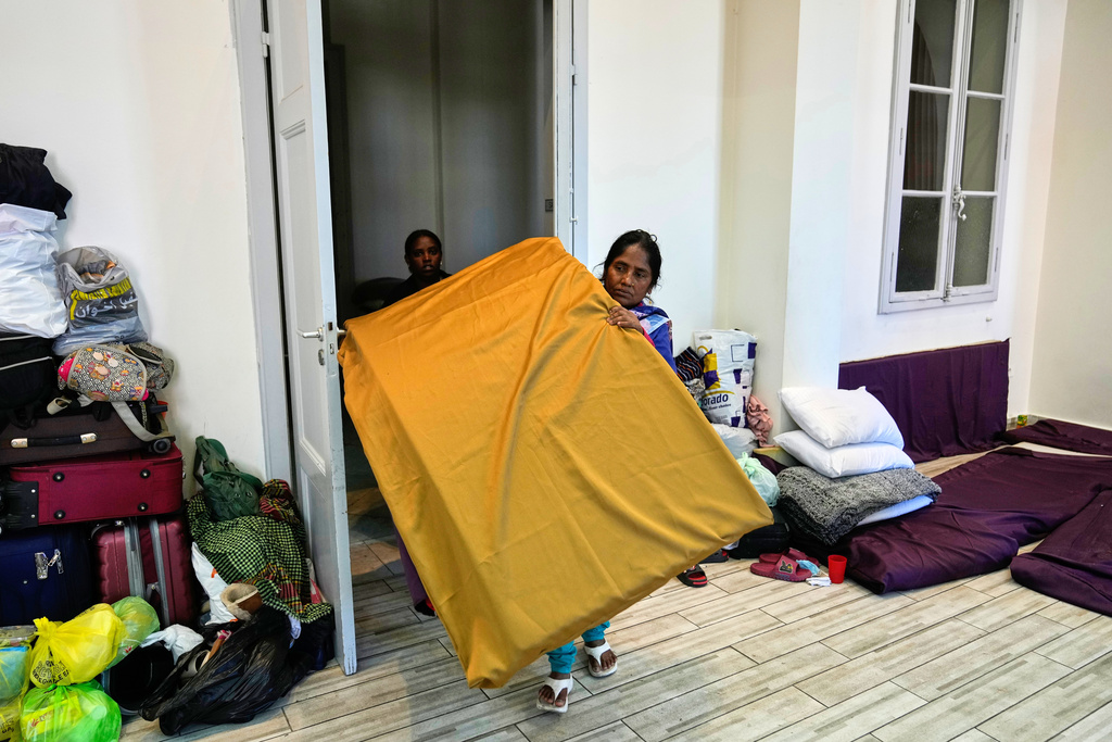 A displaced migrant woman who among many others fled Israeli strikes in southern and eastern Lebanon and Beirut's southern suburbs carries mattresses at Saint Joseph Church, which has been turned into a shelter for displaced migrants, mostly from African nations, in Beirut, Wednesday, March 11, 2026. (AP Photo/Hussein Malla)