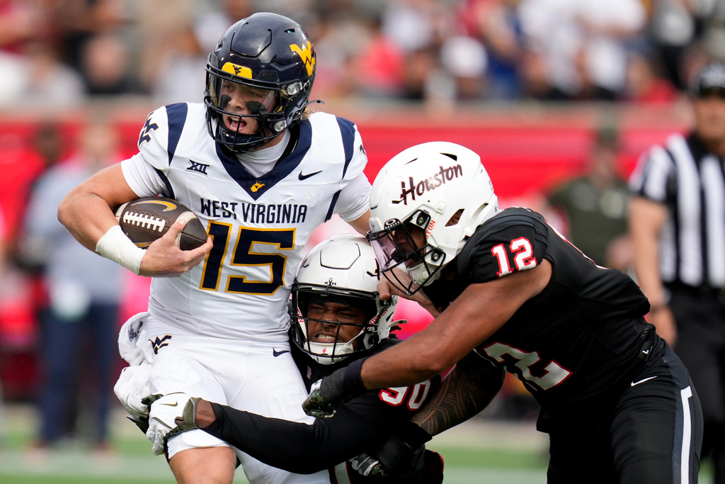 West Virginia quarterback Scotty Fox Jr. (15) is tackled by Houston defensive lineman Eddie Walls III, bottom, and linebacker Sione Fotu during the first half of an NCAA college football game, Saturday, Nov. 1, 2025, in Houston. (AP Photo/Eric Christian Smith)