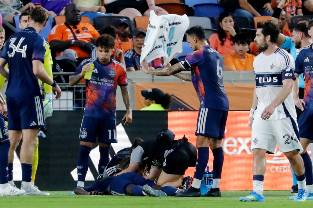 Houston Dynamo FC midfielder Jose Artur (6) fans the air with a towel over defender Diadie Samassekou, center on ground, as he is attended to by medical personnel after an apparent injury during the first half of an MLS soccer match against Vancouver Whitecaps FC, Saturday, May 16, 2026, in Houston. (AP Photo/Michael Wyke)