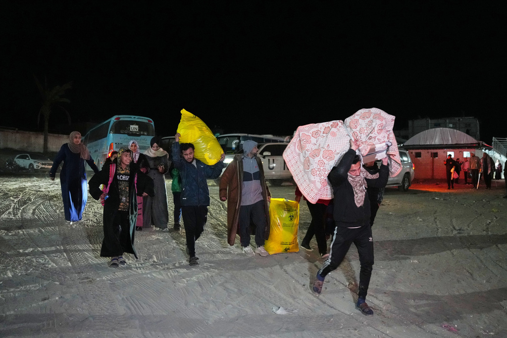 Palestinians carry the belongings of relatives arriving in Gaza from Egypt following the long-awaited reopening of the Rafah border crossing, in Khan Younis, southern Gaza Strip, early Thursday, Feb. 5, 2026. (AP Photo/Abdel Kareem Hana)