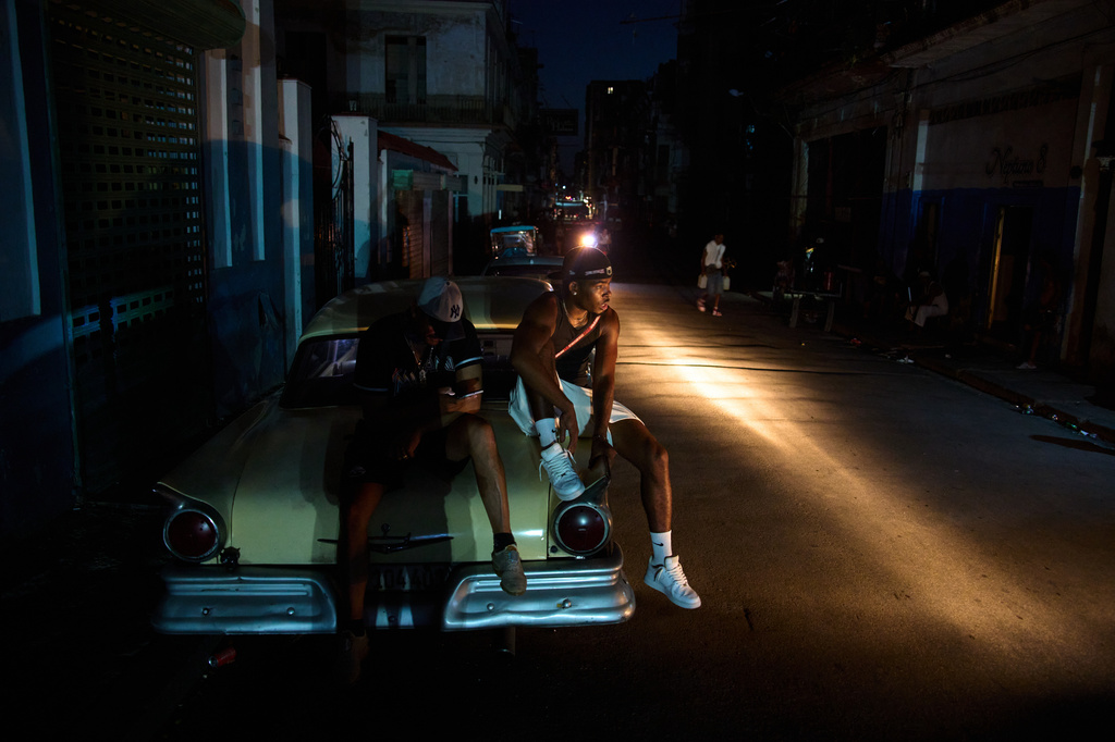 Men sit on the trunk of a car during a blackout in Havana, Cuba, Tuesday, July 14, 2026. (AP Photo/Ramon Espinosa)