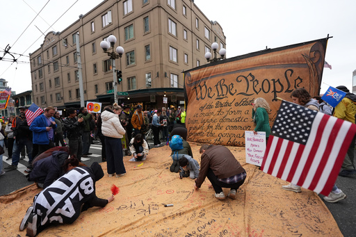 People are signing a giant Constitution as they take part in a "No Kings" protest Saturday, Oct. 18, 2025, in Seattle. (AP Photo/Lindsey Wasson) People are signing a giant Constitution as they take part in a "No Kings" protest Saturday, Oct. 18, 2025, in Seattle. (AP Photo/Lindsey Wasson)