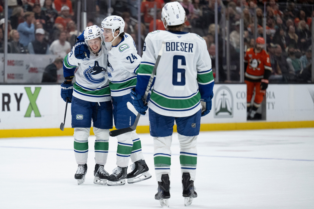 Vancouver Canucks center Marco Rossi, left, celebrates his game-winning overtime goal with defenseman Zeev Buium, center, in an NHL hockey game against the Anaheim Ducks, Sunday, April 12, 2026, in Anaheim, Calif. (AP Photo/Kyusung Gong)