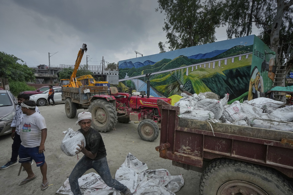 A worker loads sandbags on a truck after the river Yamuna, swollen by incessant rain in the higher regions, overran its banks, in New Delhi, India, Tuesday, Sept. 2, 2025. (AP Photo/Manish Swarup)