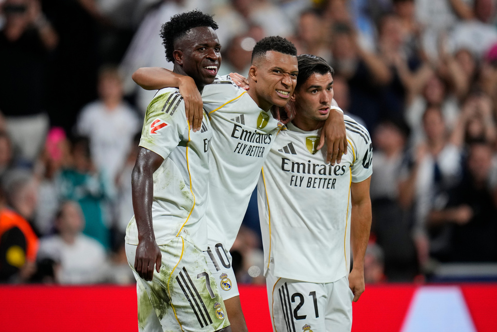 Real Madrid's Kylian Mbappe, centre, celebrates with Vinicius Junior, left, and Brahim Diaz after scoring his side's third goal during the Spanish La Liga soccer match between Real Madrid and Villarreal at the Santiago Bernabeu stadium in Madrid, Spain, Saturday, Oct. 4, 2025. (AP Photo/Manu Fernandez)