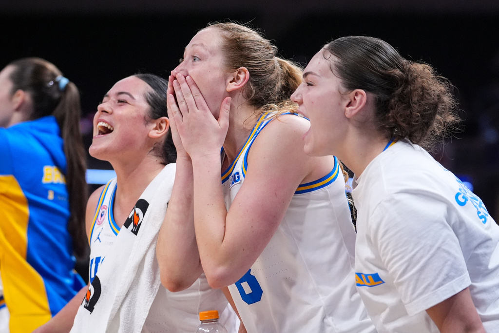 UCLA guard Charlisse Leger-Walker, left, guard Gianna Kneepkens, center, and guard Christina Karamouzi celebrate on the bench in the second half of an NCAA college basketball game in the finals of the Big Ten Conference tournament, Sunday, March 8, 2026 in Indianapolis. (AP Photo/Michael Conroy)