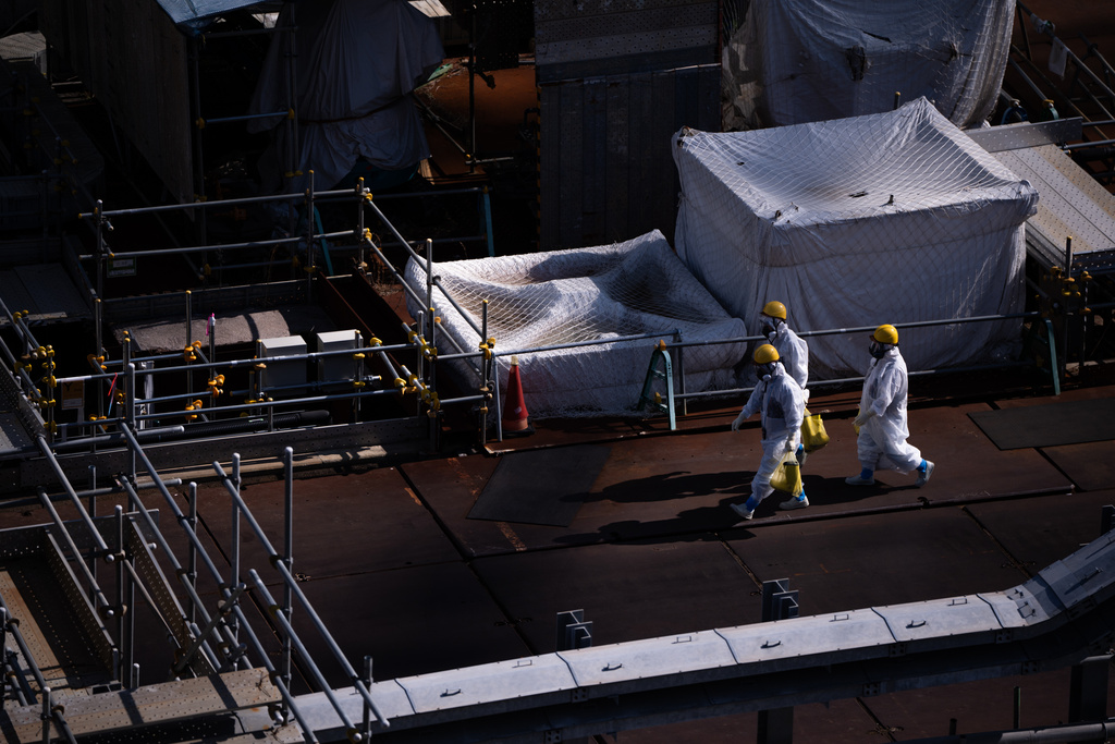 Workers walk through the Fukushima Daiichi nuclear power plant, operated by Tokyo Electric Power Company (TEPCO), in Okuma, Fukushima Prefecture, Thursday, Feb. 12, 2026. (AP Photo/Louise Delmotte)