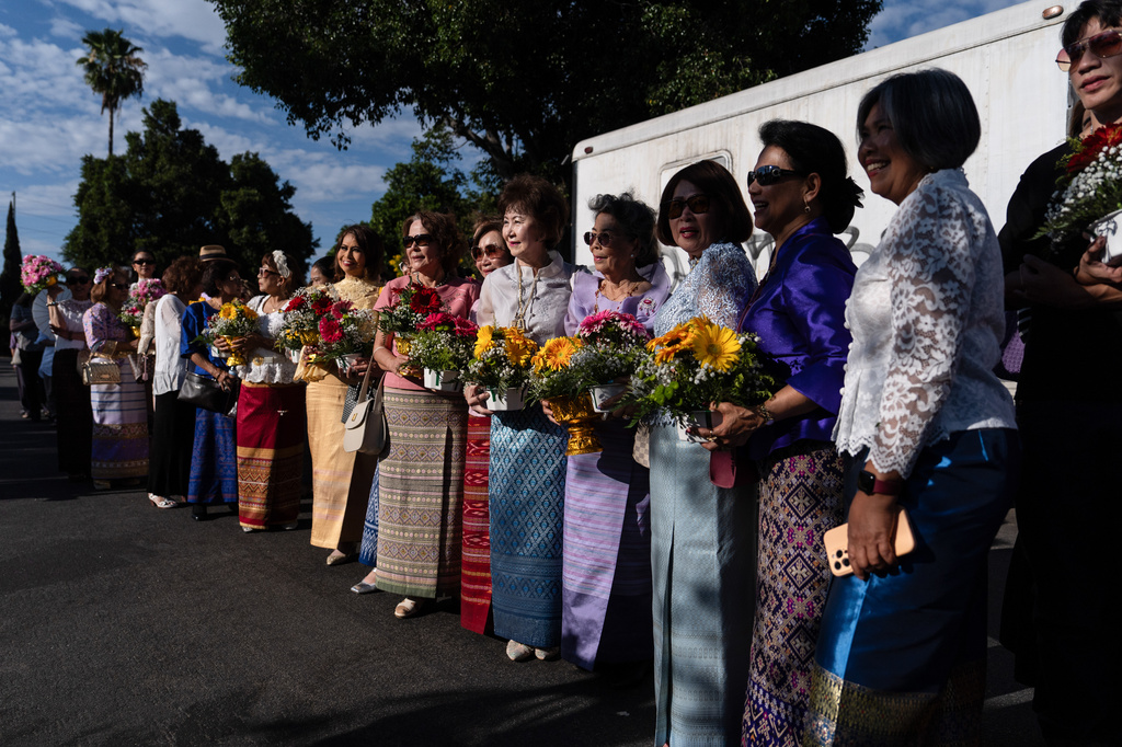 Attendees hold flowers while waiting to greet Bhikkhu Pannakara, a Buddhist monk who led a Walk for Peace from Fort Worth, Texas, to Washington, D.C., during an event at Wat Thai of Los Angeles in the North Hollywood section of Los Angeles, Monday, July 13, 2026. (AP Photo/Jae C. Hong)