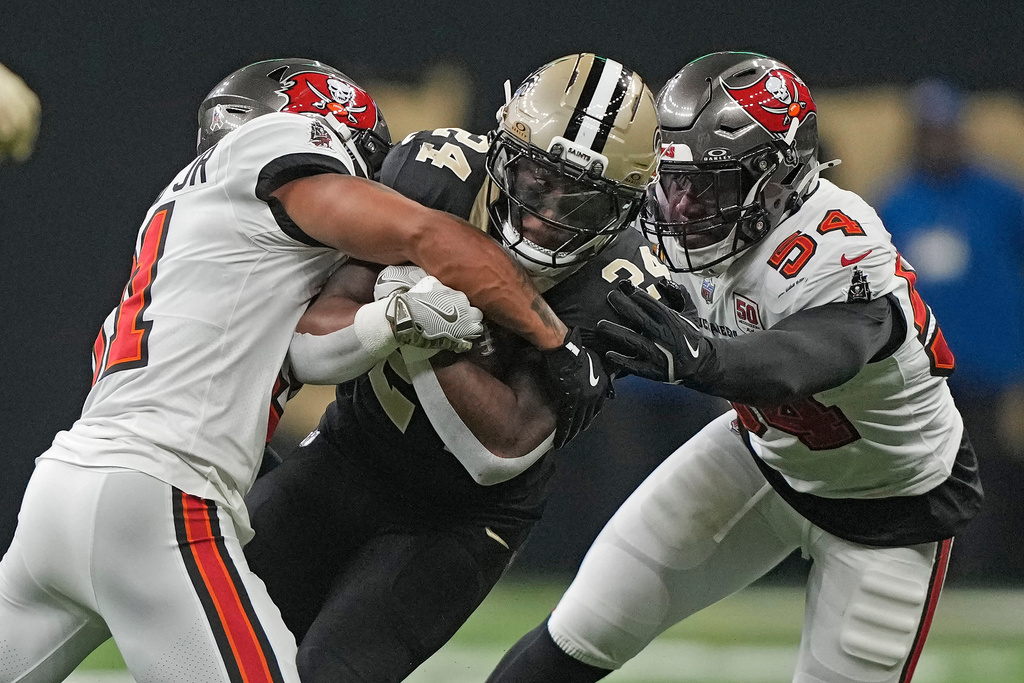 New Orleans Saints running back Devin Neal (24) is stopped by Tampa Bay Buccaneers safety Antoine Winfield Jr. (31) and linebacker Lavonte David (54) during the first half of an NFL football game Sunday, Oct. 26, 2025, in New Orleans. (AP Photo/Gerald Herbert)