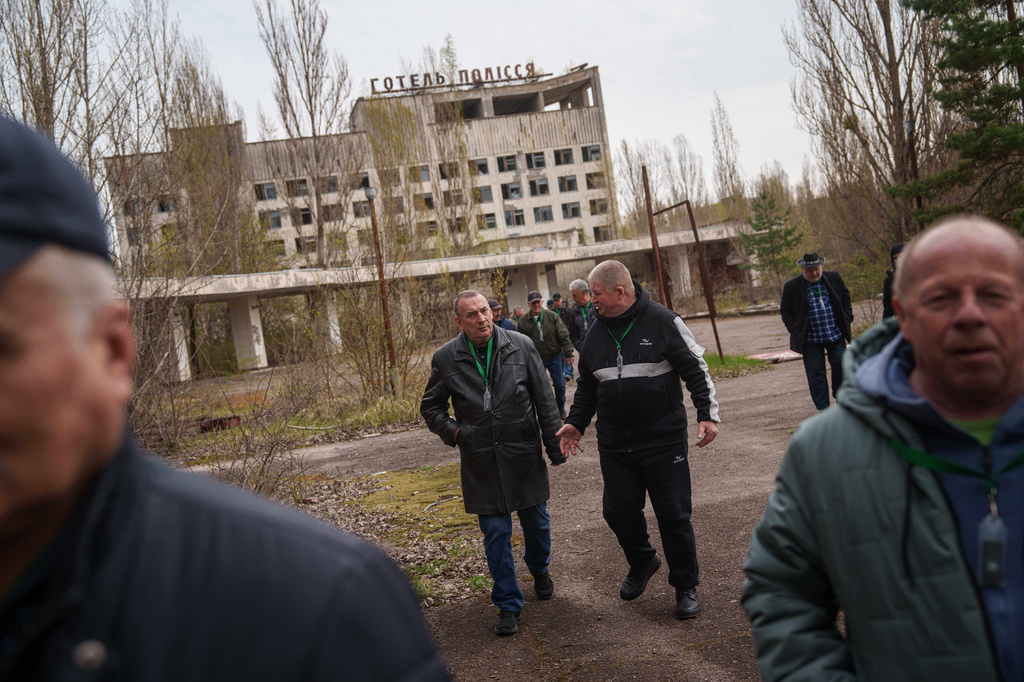 Stanislav Tolumnyi, 65, left, and Mykola Chudak, 66, walk with fellow workers who helped clean up contamination from the 1986 Chernobyl nuclear disaster, in the nearby abandoned town of Prypiat, Ukraine, Tuesday, April 21, 2026, ahead of the 40th anniversary of the accident. (AP Photo/Evgeniy Maloletka)