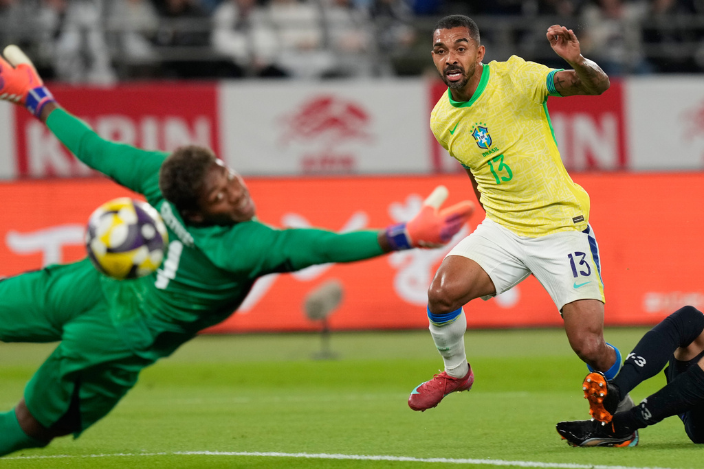 Brazil's Paulo Henrique, right, scores a goal past Japan's goalkeeper Zion Suzuki during the friendly soccer match between Japan and Brazil Tuesday, Oct. 14, 2025, in Tokyo. (AP Photo/Eugene Hoshiko)