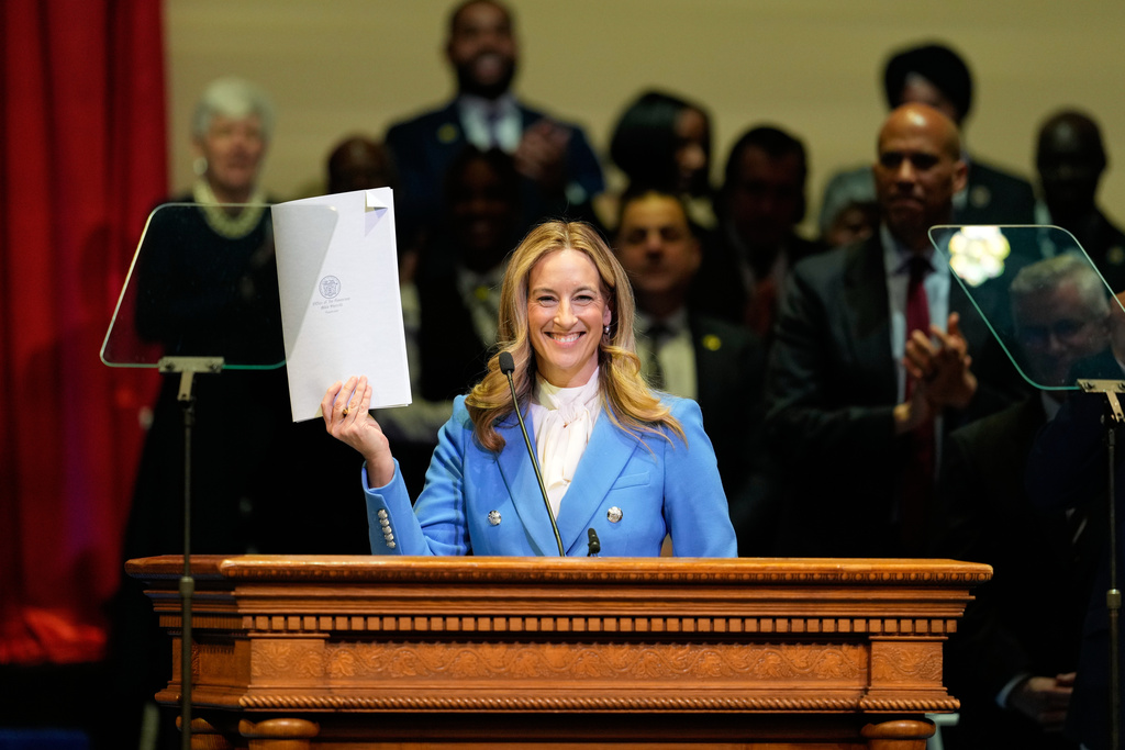 New Jersey Gov. Mikie Sherrill holds up a just signed executive order during her inauguration ceremony in Newark, N.J., Tuesday, Jan. 20, 2026. (AP Photo/Seth Wenig)