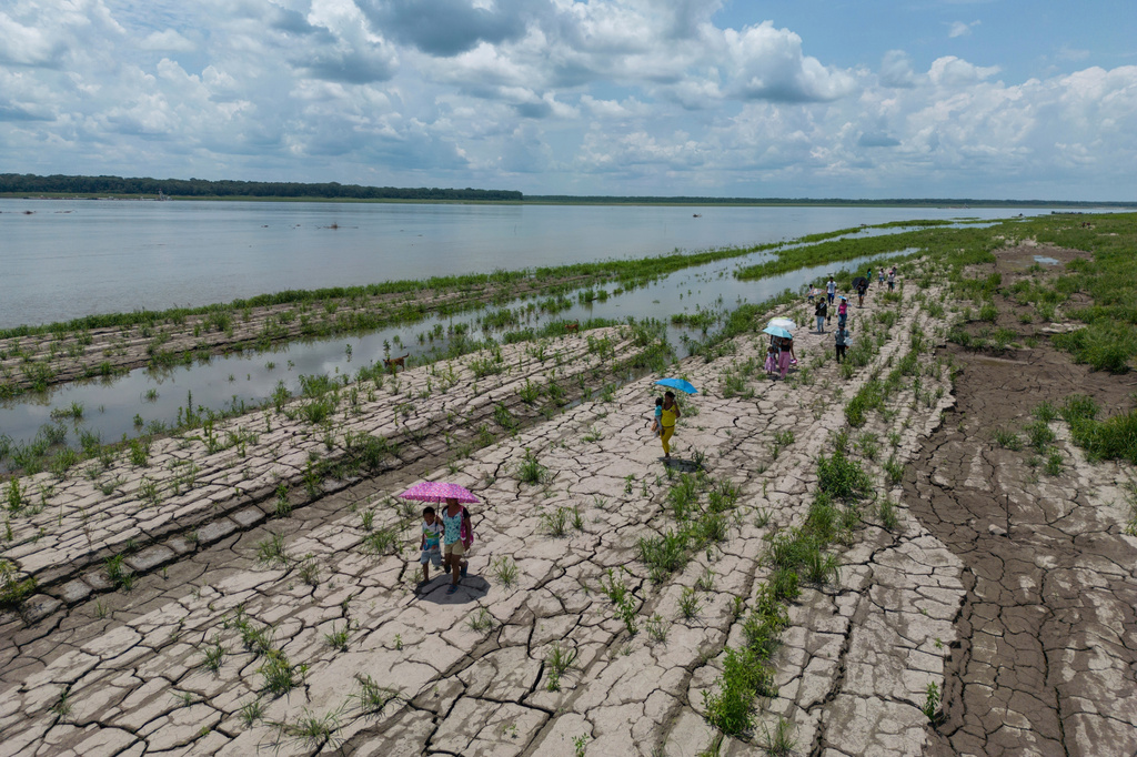 FILE - People walk through a part of the Amazon River that shows signs of drought in Santa Sofia, on the outskirts of Leticia, Colombia, Oct. 20, 2024. (AP Photo/Ivan Valencia, File)