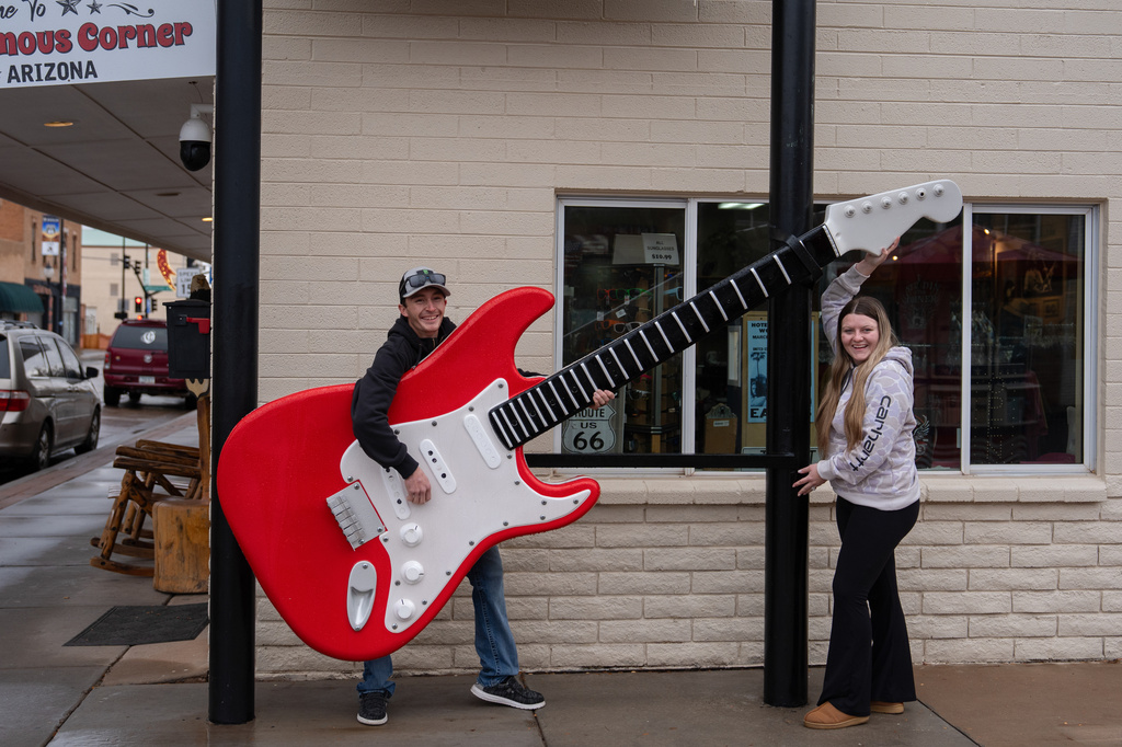Newlyweds Keith Hedberg, left, and his wife, Adriana, traveling from Syracuse, Kansas, on their honeymoon, pose for photos with a large guitar installation outside a gift shop in Winslow, Ariz., a town on historic Route 66, Thursday, Nov. 20, 2025. (AP Photo/Jae C. Hong)