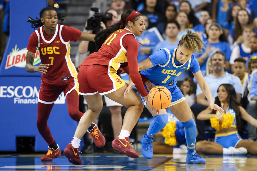 UCLA guard Kiki Rice (1) battles for the ball against Southern California guard Kennedy Smith (11) as forward Yakiya Milton (7) watches during the first half of an NCAA college basketball game Saturday, Jan. 3, 2026, in Los Angeles. (AP Photo/Jessie Alcheh)