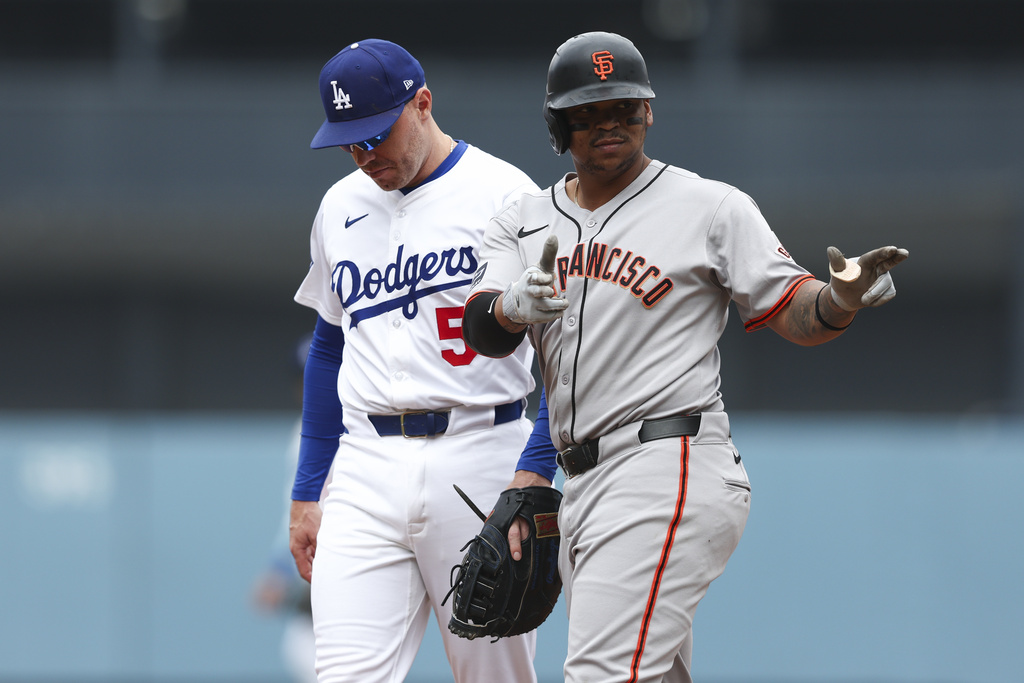 San Francisco Giants designated hitter Rafael Devers, right, gestures after hitting a single as Los Angeles Dodgers first baseman Freddie Freeman (5) looks on during the first inning of a baseball game, Sunday, Sept. 21, 2025, in Los Angeles. (AP Photo/Jessie Alcheh)