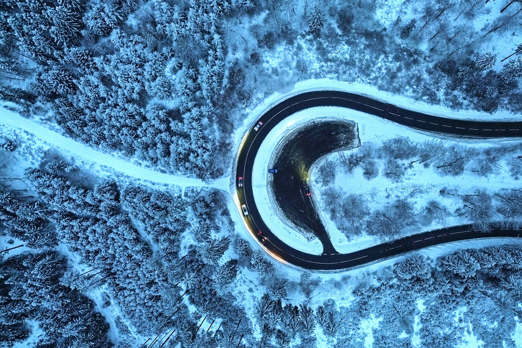 Cars drive around a curve in a snow covered forest of the Taunus region near Frankfurt, Germany, Tuesday, Jan. 6, 2026. (AP Photo/Michael Probst)
