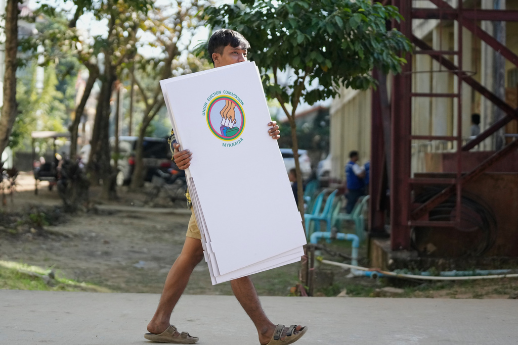 A volunteer of the Union Election Commission carries election materials as they prepare to set up a polling station opened at a school one day ahead of the first phase of the general election in Yangon, Myanmar, Saturday, Dec. 27, 2025. (AP Photo/Thein Zaw)