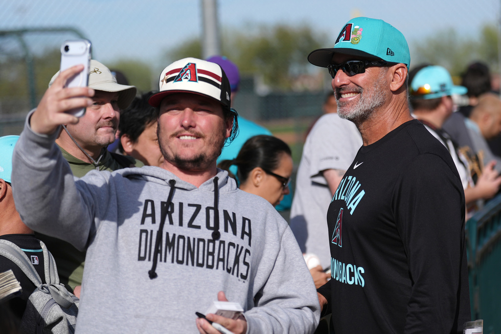 Arizona Diamondbacks manager Torey Lovullo smiles as he takes a selfie with a fan during spring training baseball Thursday, Feb. 12, 2026, in Scottsdale, Ariz. (AP Photo/Ross D. Franklin)