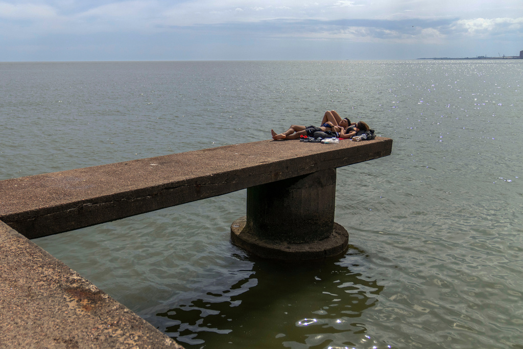 People sunbathe at the seaside in Montevideo, Uruguay, Thursday, Nov. 27, 2025. (AP Photo/Matilde Campodonico)