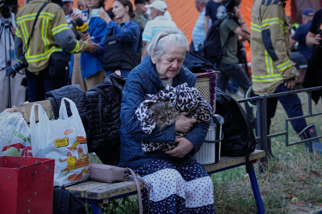 An elderly woman holds her car as she sits with her belongings in front of heavily damaged residential buildings after an overnight Russian attack, in Kyiv, Ukraine, Thursday, Aug. 20, 2026. (AP Photo/Efrem Lukatsky)