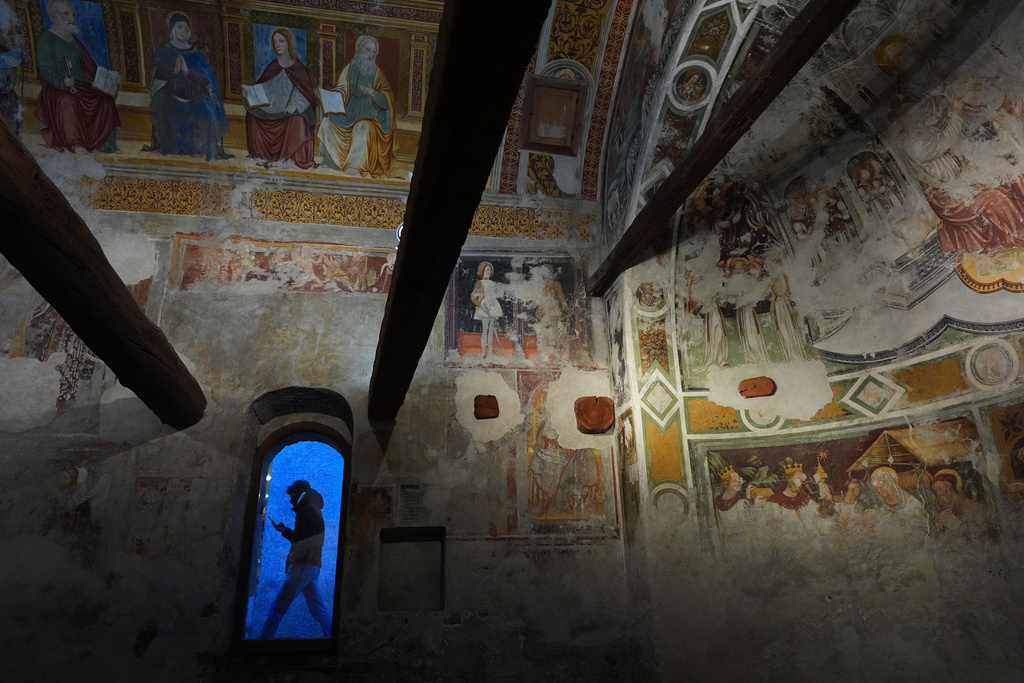 A person walks past outside Santo Spirito church, where centuries-old frescoes adorn the walls, during the 2026 Winter Olympics, in Bormio, Italy, Tuesday, Feb. 10, 2026. (AP Photo/Rebecca Blackwell)