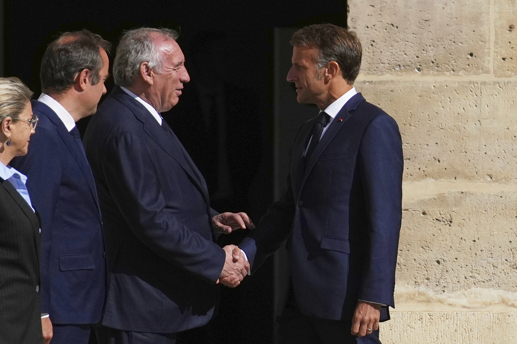 France's President Emmanuel Macron, right, shakes hand with France's Prime Minister Francois Bayrou during the farewell ceremony of Chief of Staff of the French Armed Forces Thierry Burkhard, in the courtyard of the Invalides, in Paris, France, Friday, Sept. 5, 2025. (AP Photo/Christophe Ena, Pool)