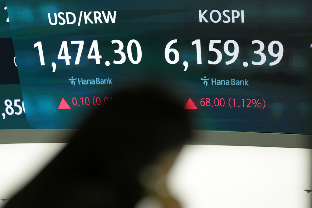 A dealer stands near the screen showing the Korea Composite Stock Price Index (KOSPI), right, and the foreign exchange rate between U.S. dollar and South Korean won at a dealing room of Hana Bank, in Seoul, South Korea, Thursday, April 16, 2026. (AP Photo/Lee Jin-man)