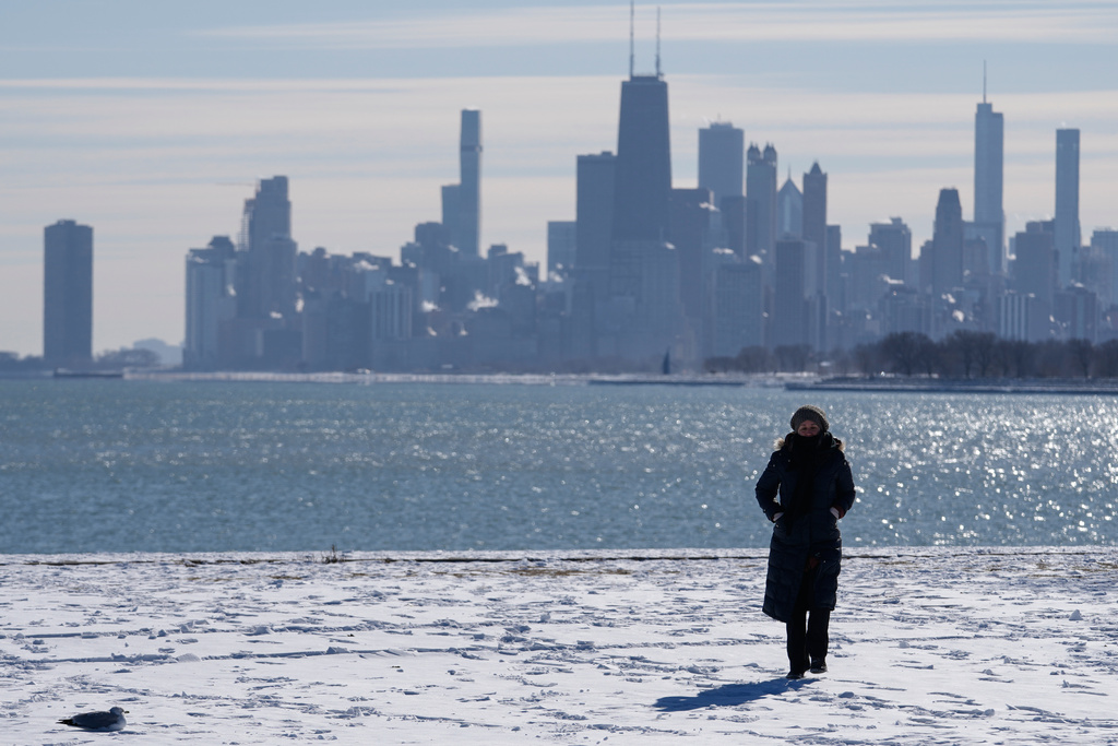 A person bundles up as she takes a walk during a cold weather day in the snow-covered sand at Lake Michigan in Chicago, Wednesday, Jan. 28, 2026. (AP Photo/Nam Y. Huh)