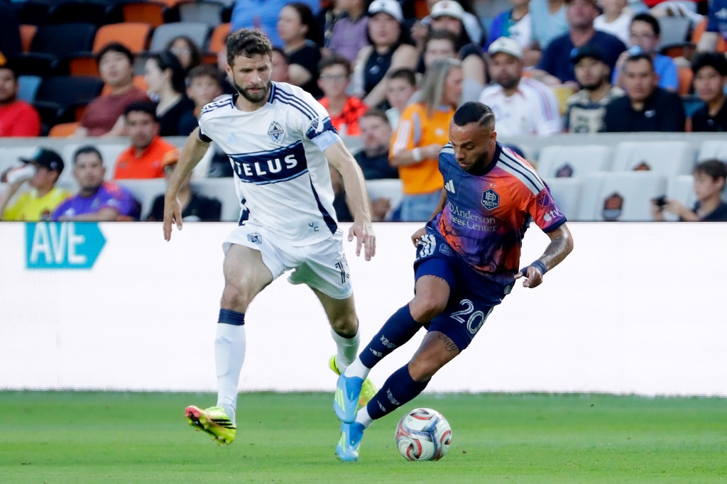 Houston Dynamo FC midfielder Guilherme Santos, right, moves the ball past Vancouver Whitecaps FC midfielder Thomas Muller during the first half of an MLS soccer match, Saturday, May 16, 2026, in Houston. (AP Photo/Michael Wyke)