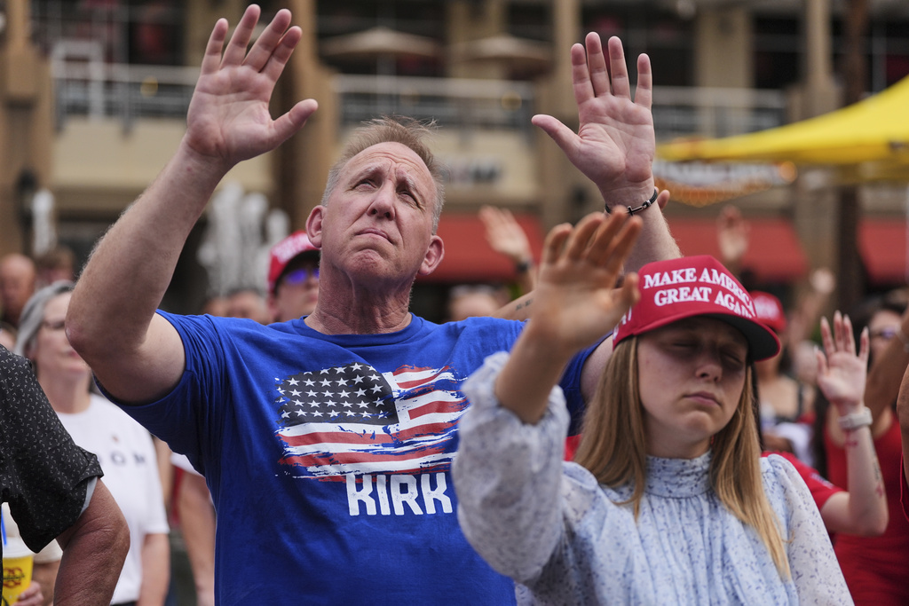 People listen to a worship song in the overflow area outside before a memorial for conservative activist Charlie Kirk, Sunday, Sept. 21, 2025, at State Farm Stadium in Glendale, Ariz. (AP Photo/Jae C. Hong)