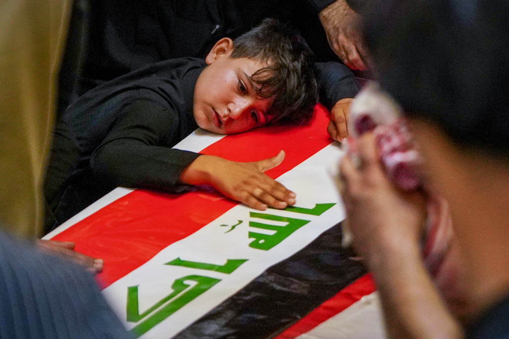 A child rests his head on the coffin of a Popular Mobilization Forces fighter draped in the Iraqi flag during a funeral for Popular Mobilization Forces fighters killed in airstrikes on PMF bases in Najaf, Iraq, Thursday, July 30, 2026. (AP Photo/Anmar Khalil)