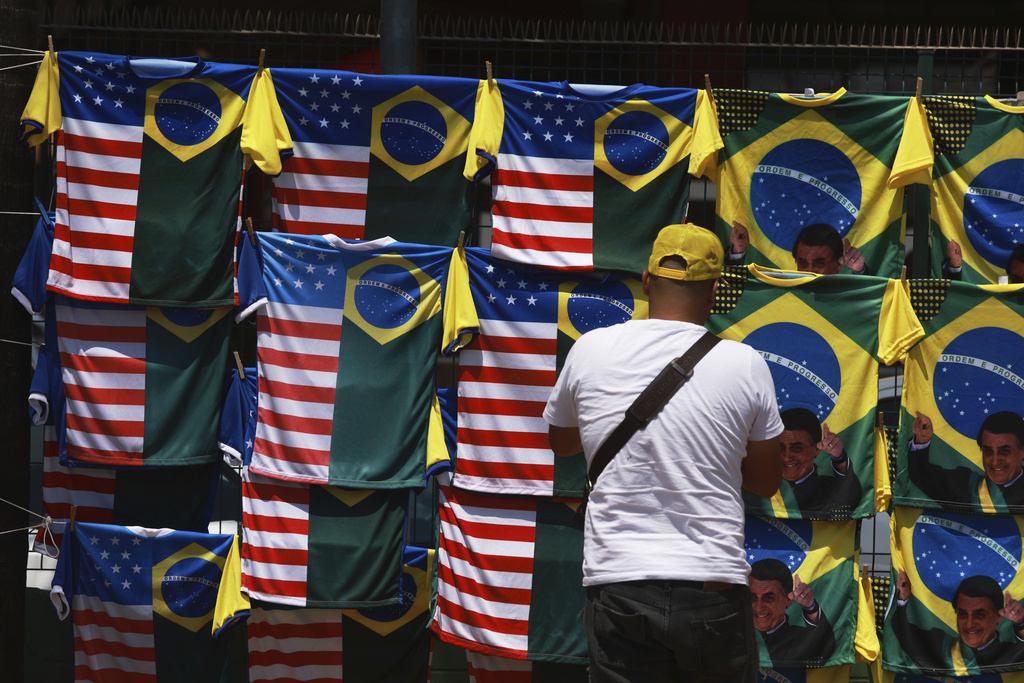 A vendor displays dual flag jerseys featuring the Brazilian and U.S. flag, outside the condominium where former President Jair Bolsonaro is under house arrest in Brasilia, Brazil, Thursday, Sept. 11, 2025. (AP Photo/Luis Nova)