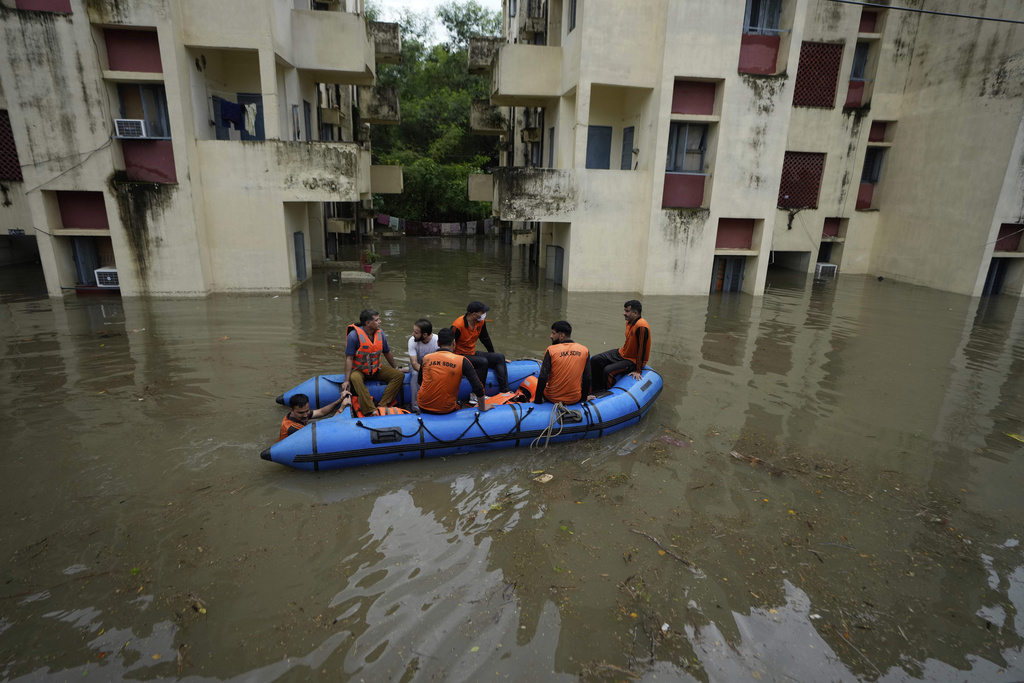 Members of the State Disaster Response Force (SDRF) navigate a boat to rescue students stranded in a hostel after floodwaters submerged the ground floor of the complex in Jammu, India, Sunday, Aug 24, 2025.(AP Photo/Channi Anand)