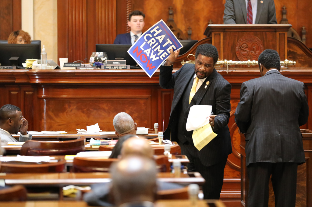 Democratic South Carolina Rep. Wendell Gillard walks back to his desk with a sign after giving a speech during the redistricting debate on Tuesday. May 19, 2026, in Columbia, S.C. (AP Photo/Jeffrey Collins)