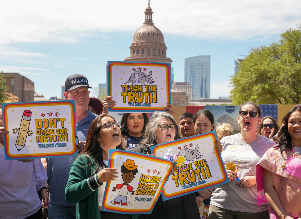 People hold signs reading "Teach the Truth" and "Don't erase our history" during a rally on the Capitol Mall outside the Barbara Jordan State Office Building, where the State Board of Education meets, Tuesday, April 7, 2026, in Austin, Texas. (Jay Janner/Austin American-Statesman via AP)