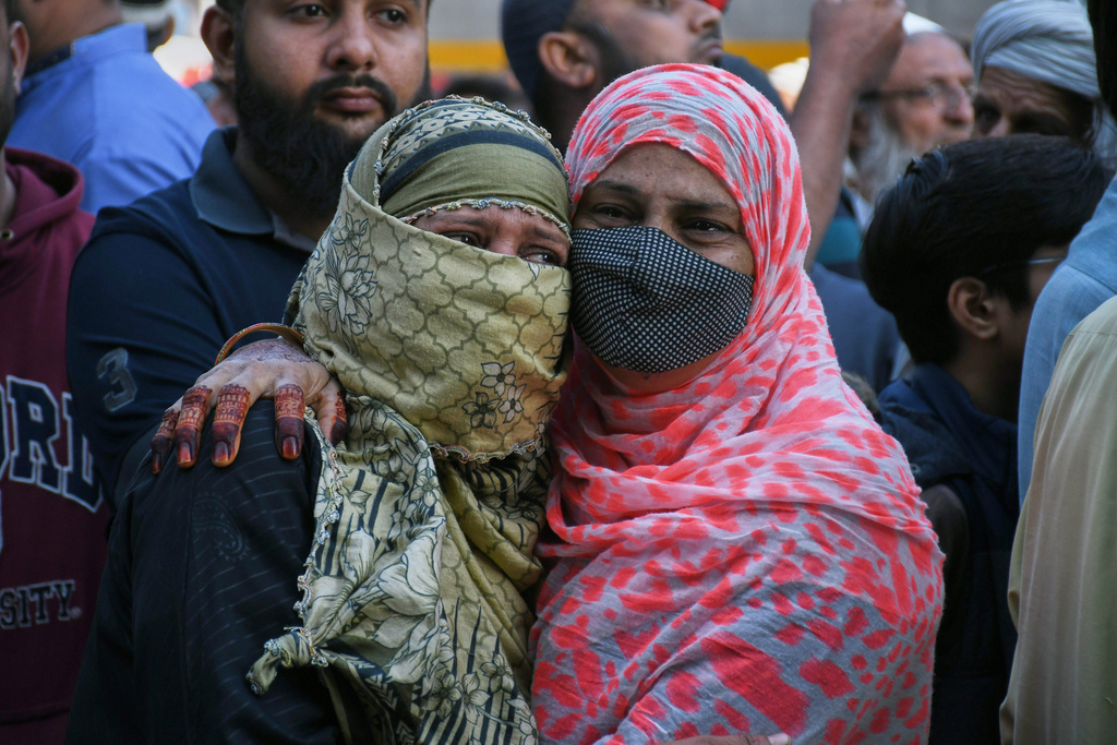 Family members of missing persons weep as they wait near the site of a burnt building of a multi-story shopping plaza following a massive fire in Karachi, Pakistan, Monday, Jan. 19, 2026. (AP Photo/Ali Raza)