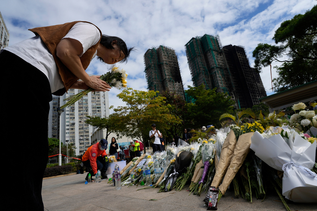 A woman bows as she offers flowers near the site of a deadly fire at Wang Fuk Court, a residential estate in the Tai Po district of Hong Kong's New Territories on Tuesday, Dec. 2, 2025. (AP Photo/Ng Han Guan)